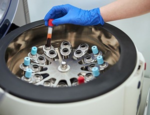 Gloved hand placing blood in centrifuge