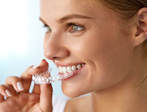 Woman placing her Invisalign tray after cosmetic dentistry visit