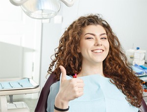 smiling woman giving a thumbs-up in the dental chair