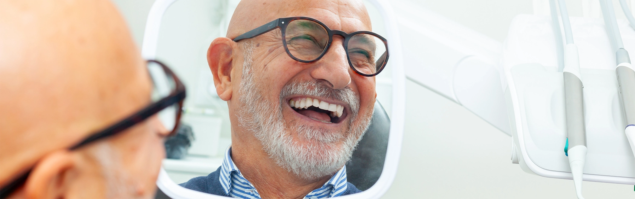 Dental patient admiring his new dentures in a mirror