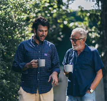 Two men walking and holding coffee mugs