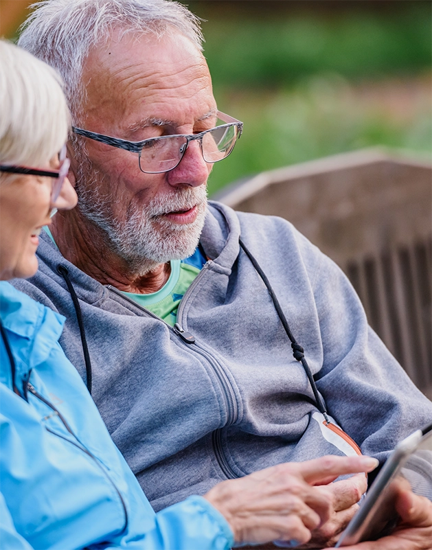 Senior looking at a tablet while sitting on a park bench