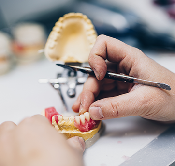 Dental lab worker making adjustments to a denture