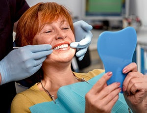 A mature woman looking at her dentures in a mirror