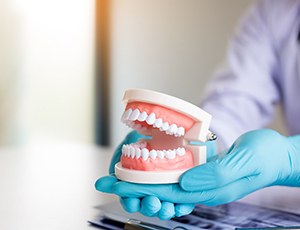 A dentist holding model dentures in their gloved hands
