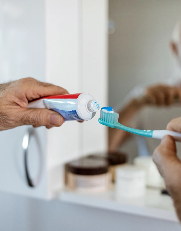 Person putting toothpaste on their toothbrush