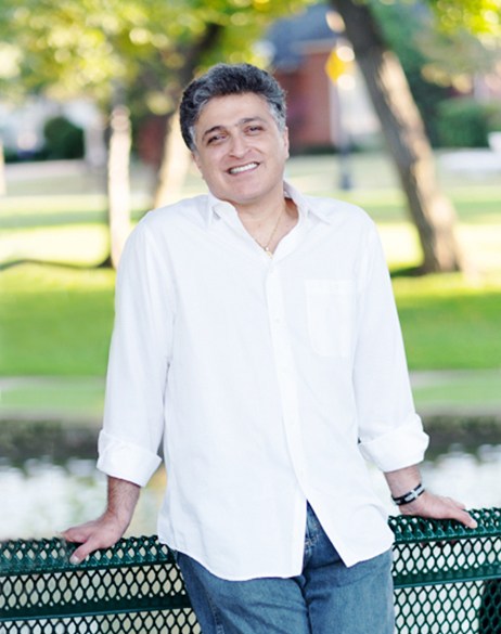 An image of Dr. Azmoodeh leaning against a fence and smiling