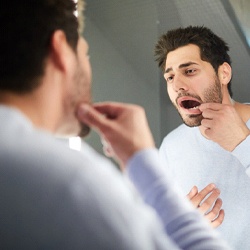 Closeup of man examining his teeth in mirror