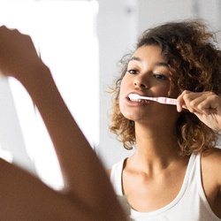 Woman in white shirt brushing her teeth in bathroom