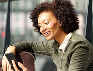 A middle-aged woman looking at her phone while seated in the airport