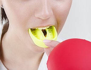 person putting a yellow mouthguard in their mouth 