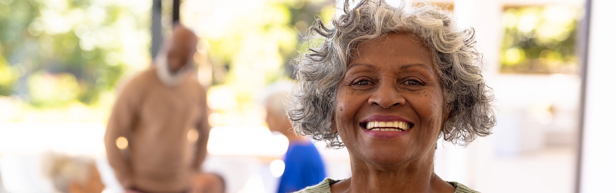 Senior woman smiling outdoors with implant dentures in Richardson