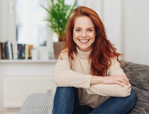 Woman with red hair sitting on couch smiling