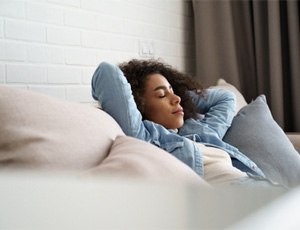 Woman in denim jacket resting on her couch
