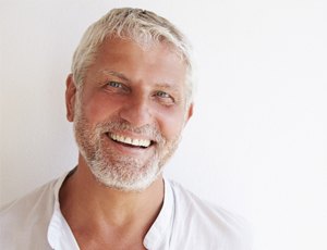 elderly man smiling with implant dentures in Richardson 
