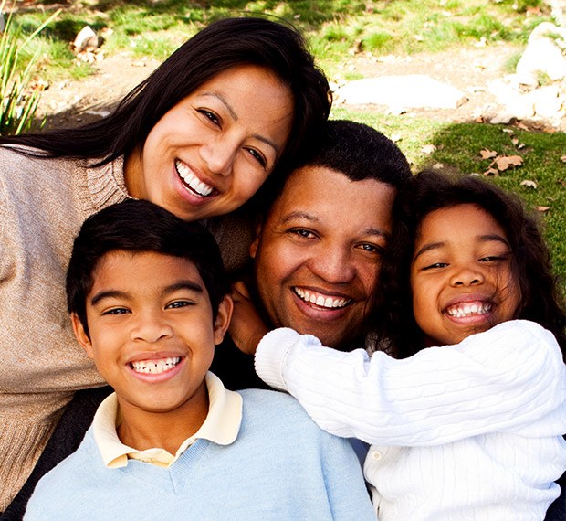 Happy family of four smiling outdoors