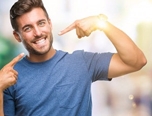 Man pointing to his Straight smile after Invisalign treatment