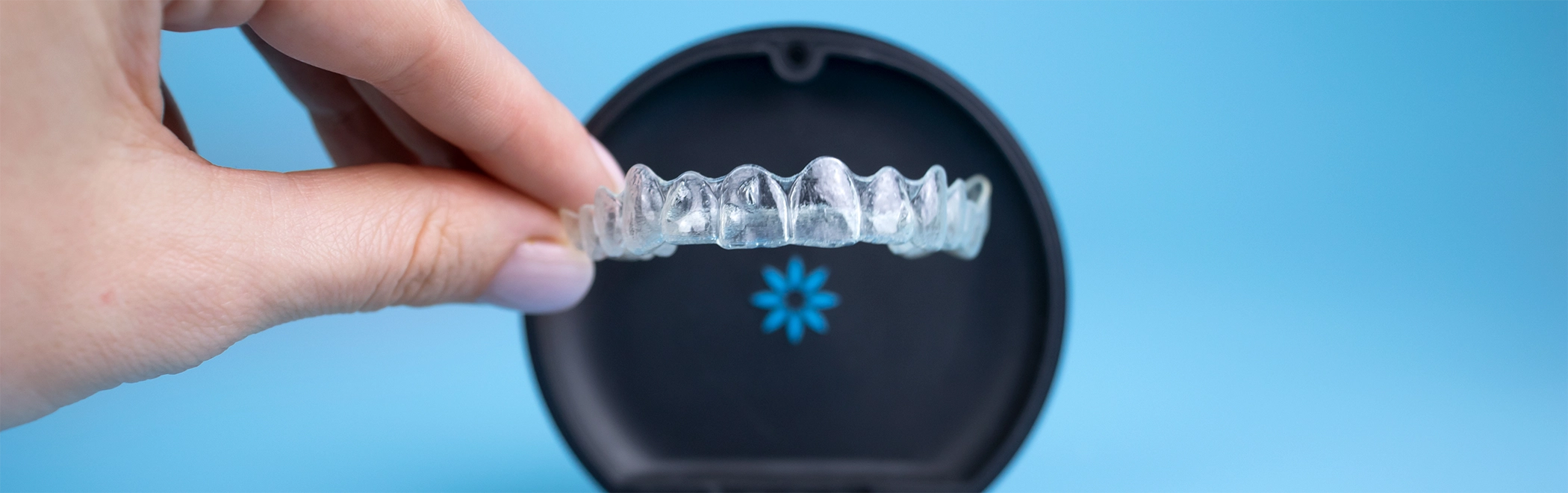 Hand placing an Invisalign clear aligner into its storage case