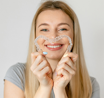 Young woman making a heart shape with her aligners