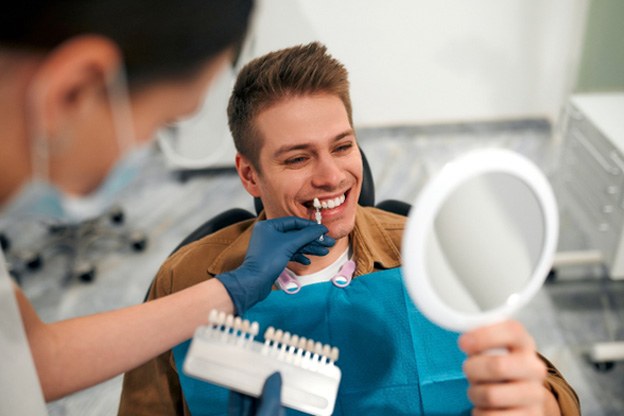 Man in dental chair with dentist checking tooth shade