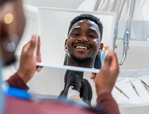 Male patient smiling in the mirror while seeing MetLife dentist in Richardson