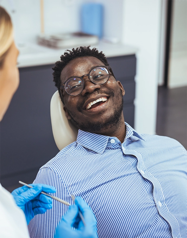 Man in the dental chair grinning at his dentist