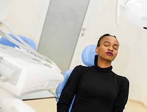 Female dental patient in chair relaxing with eyes closed