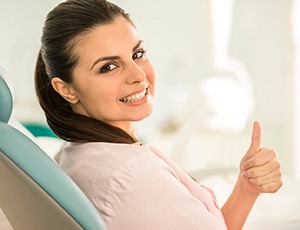 Female dental patient in pink shirt giving thumbs up