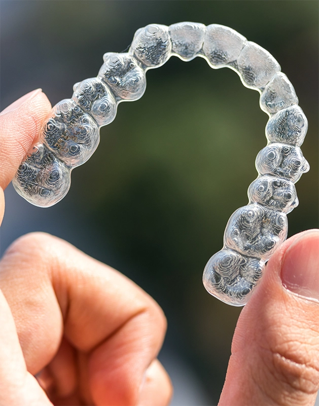 Hand holding a clear aligner