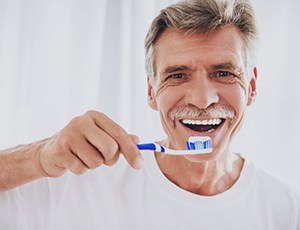 man brushing his teeth in his at-home hygiene routine