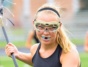 Teen girl playing lacrosse with blue sportsguard