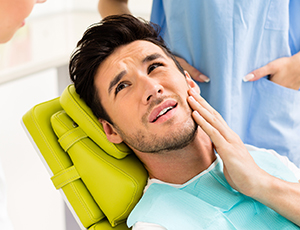 Man holding cheek in pain before emergency dentistry