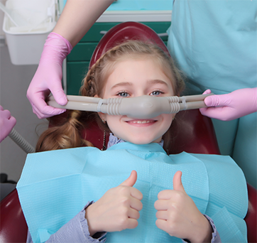 Young girl giving thumbs up while getting nitrous oxide