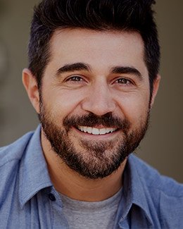 Bearded man smiling and wearing light blue shirt