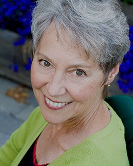 Older woman smiling and wearing green blouse