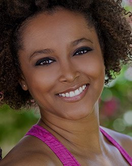 Young woman in pink blouse smiling outdoors