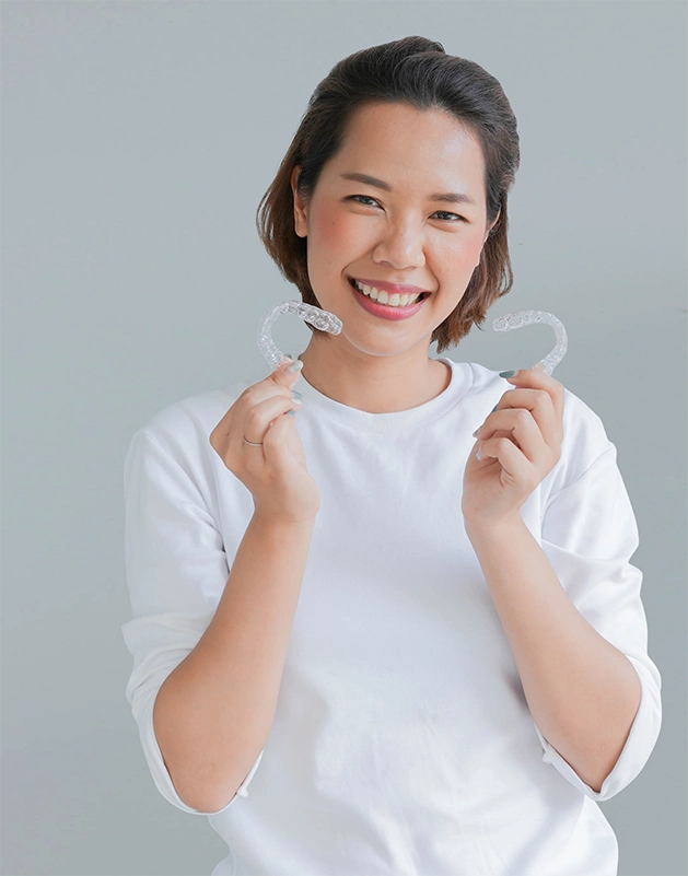 Smiling woman holding two SureSmile aligners