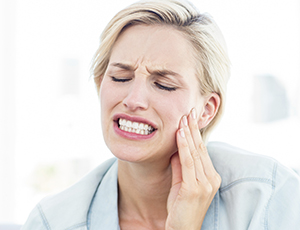 Woman holding cheek in pain before T M J therapy