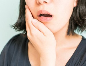 a person holding their jaw due to TMJ disorder