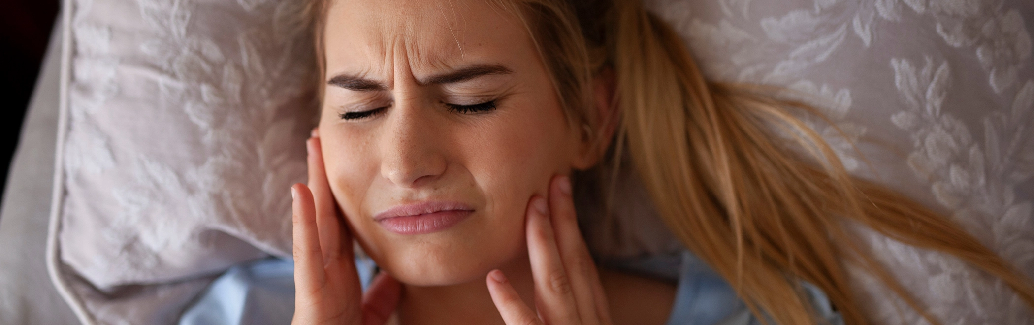 Woman holding the sides of her jaw in pain