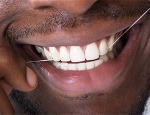 Closeup of man with veneers in Richardson flossing