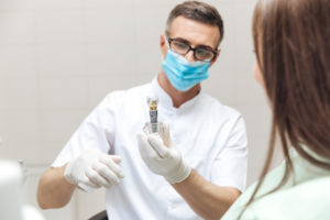 Dentist showing dental implant model to patient