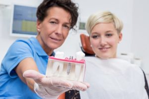 Dentist showing patient dental implant model