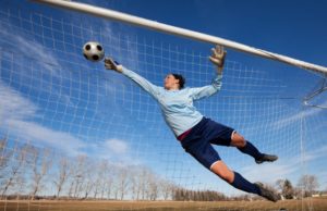 goalie blocking a soccer ball from entering net