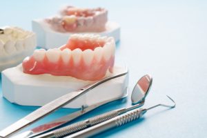 dentures sitting next to dental tools