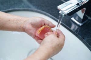 person running their dentures under water