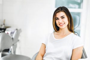 Woman in white shirt smiling in dental chair