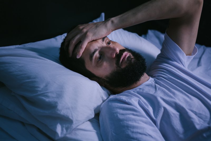 Man awake in bed due to a toothache