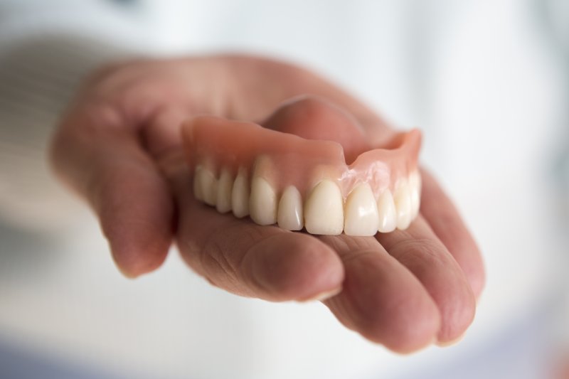 hand holding a full upper denture