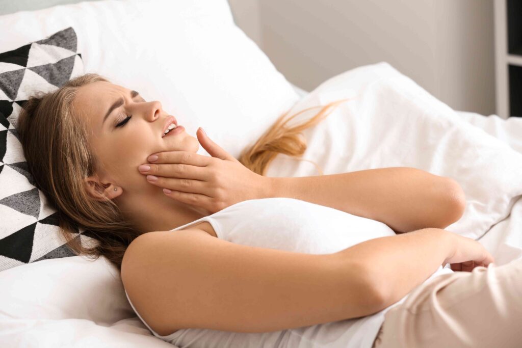 Woman with tooth pain in bed